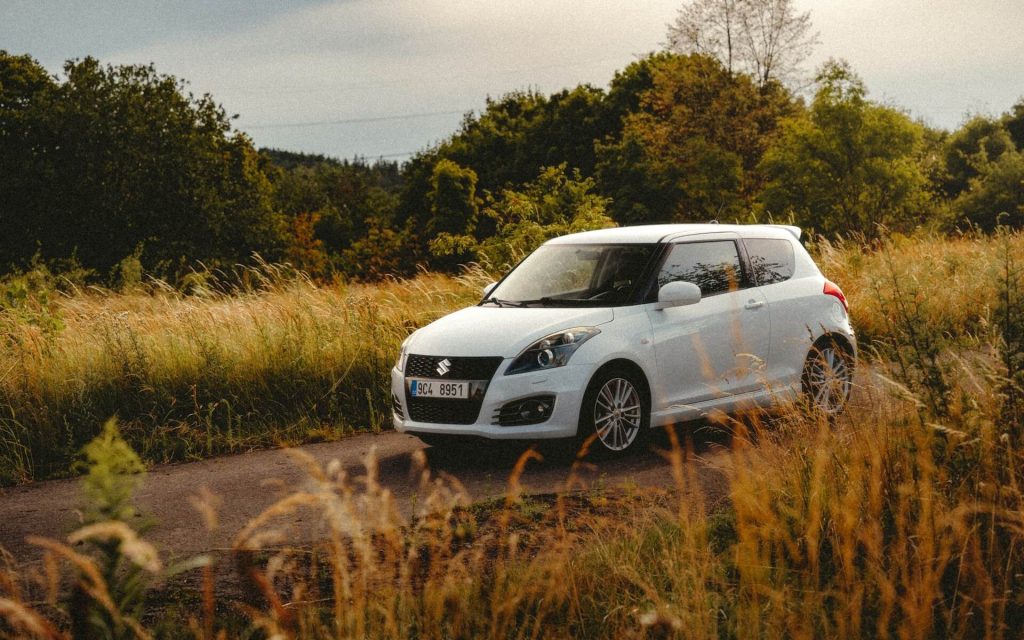 white suzuki swift on road